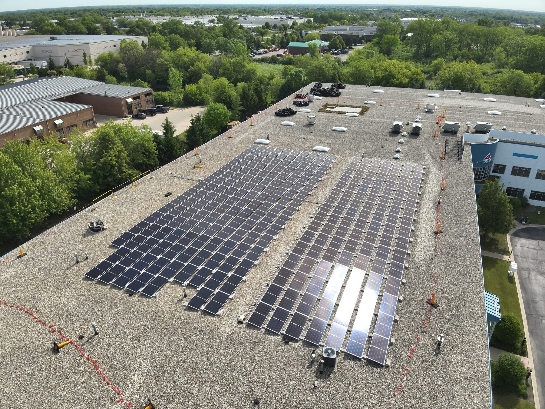 Aerial view of a commercial rooftop solar array with rooftop units and skylights around it